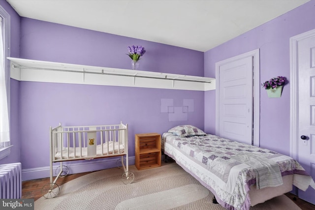 bedroom featuring wood finished floors, baseboards, and radiator heating unit