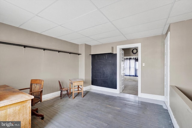 office space featuring baseboards, a drop ceiling, and wood finished floors