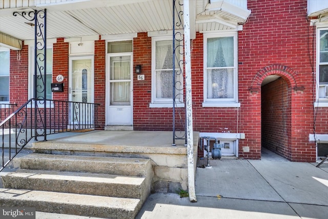 property entrance featuring brick siding and covered porch