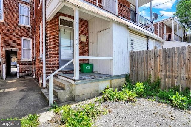 doorway to property with brick siding and fence