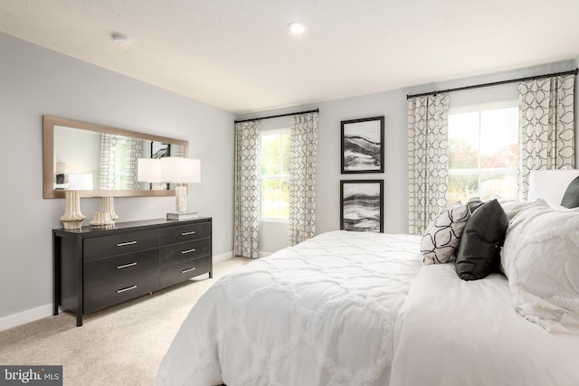 bedroom with light colored carpet, baseboards, and multiple windows