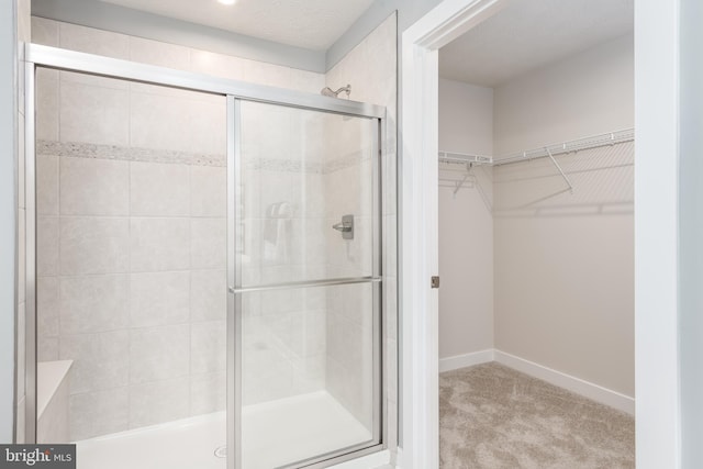 full bath with baseboards, a walk in closet, and a stall shower