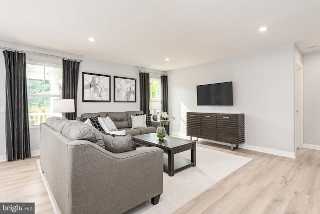 living area with baseboards, recessed lighting, and light wood-style flooring