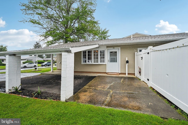 6 Swan Ln, Levittown, PA 19055 - view of exterior entry featuring fence, a carport, and roof with shingles