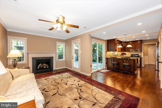 living area featuring ceiling fan, a fireplace with flush hearth, dark wood-type flooring, visible vents, and ornamental molding