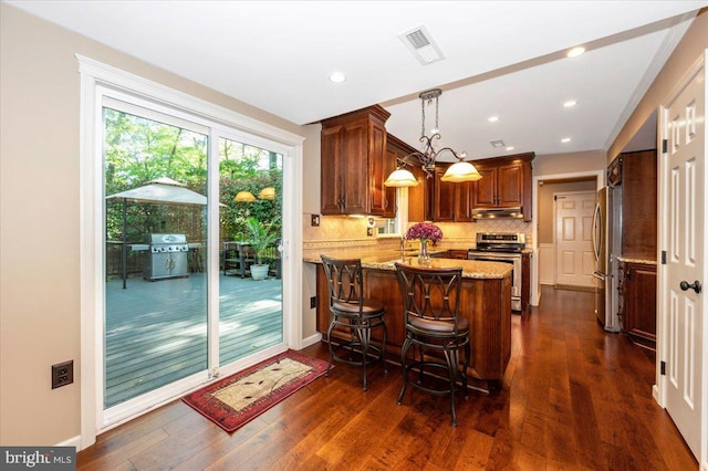 kitchen featuring backsplash, visible vents, appliances with stainless steel finishes, a peninsula, and under cabinet range hood