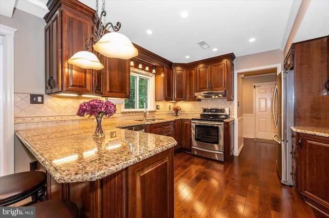 kitchen featuring appliances with stainless steel finishes, a sink, a peninsula, under cabinet range hood, and visible vents