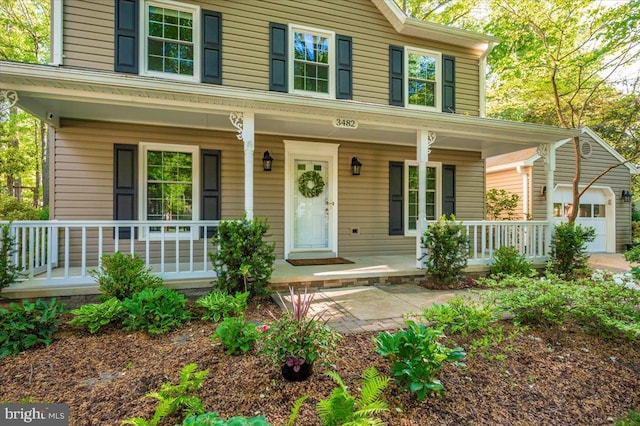 view of front of house featuring an attached garage, an outdoor structure, and covered porch
