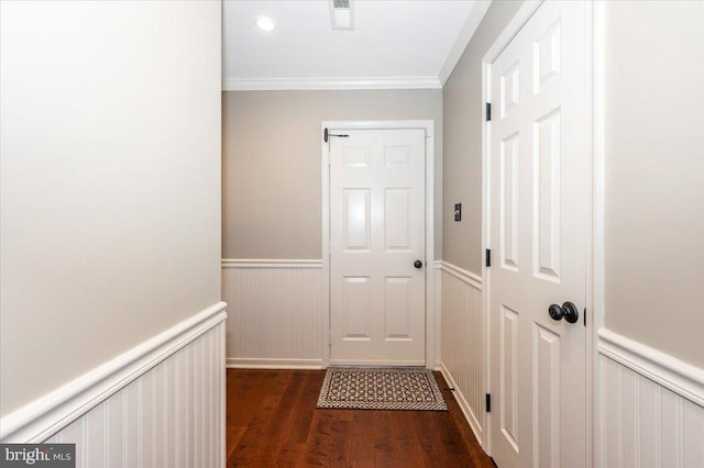doorway with ornamental molding, wainscoting, visible vents, and dark wood-type flooring