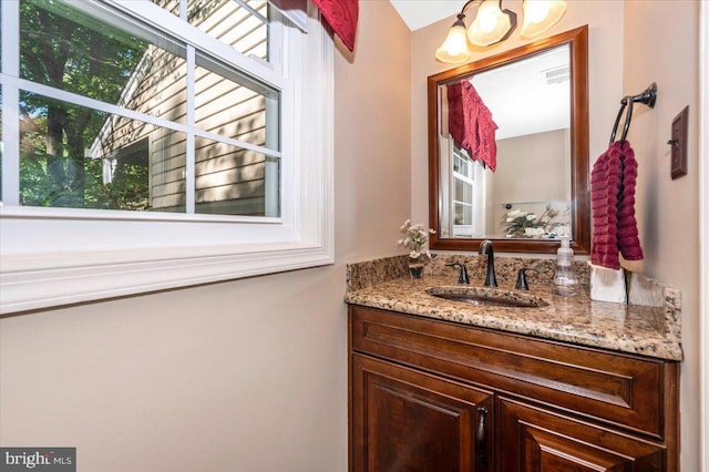 bathroom with vanity, a chandelier, and a healthy amount of sunlight