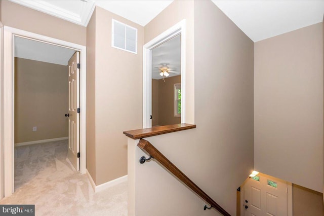 hallway with visible vents, baseboards, an upstairs landing, and light colored carpet
