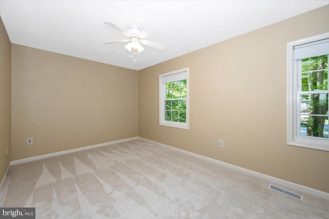 carpeted spare room featuring visible vents, baseboards, and ceiling fan