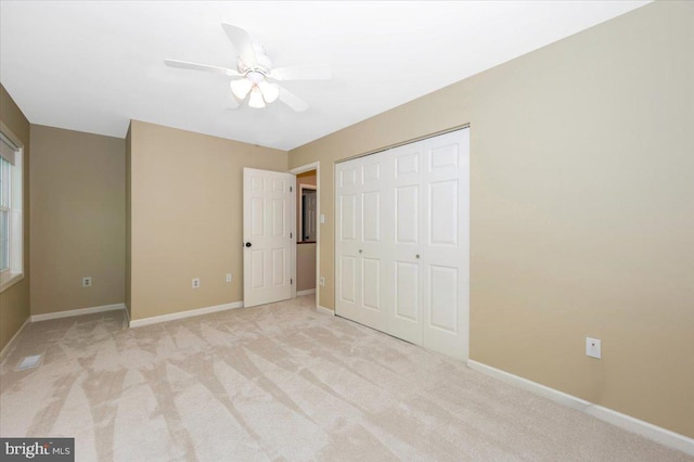 unfurnished bedroom with baseboards, ceiling fan, a closet, and light colored carpet
