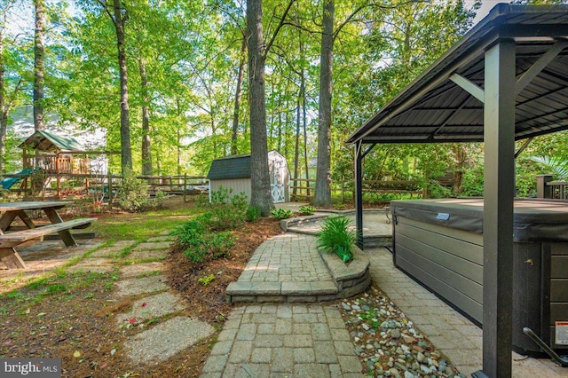 view of yard featuring an outdoor structure, a patio, a fenced backyard, a storage unit, and a hot tub