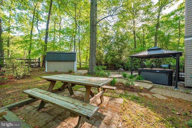 view of yard with outdoor dining space, a gazebo, a hot tub, a storage shed, and an outbuilding