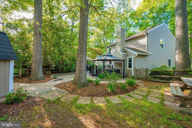 back of property featuring a gazebo, fence, a chimney, and a patio
