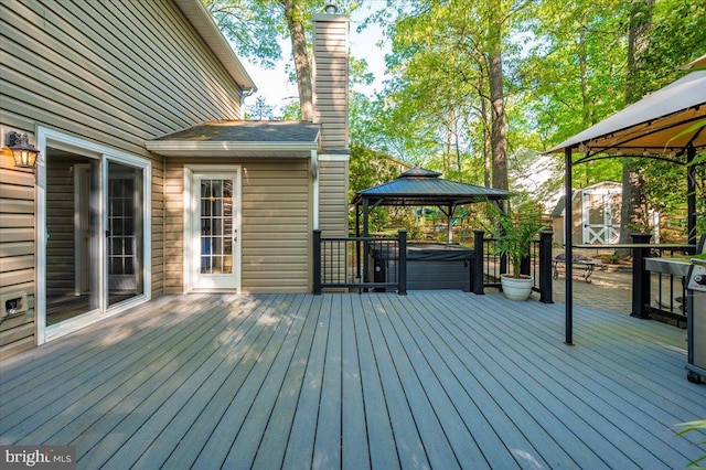 wooden deck with a storage shed, an outbuilding, a gazebo, and a hot tub