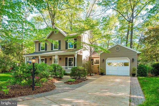 colonial home with covered porch, an attached garage, and driveway