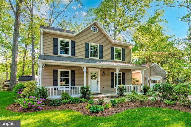 view of front of property featuring a garage, a porch, and a front yard