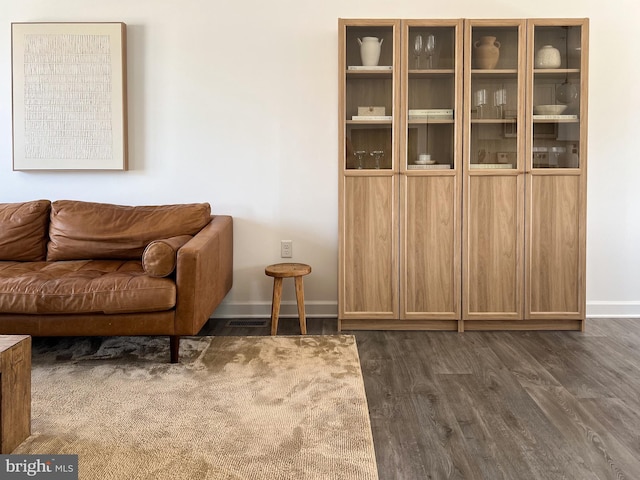 sitting room featuring baseboards and dark wood-type flooring