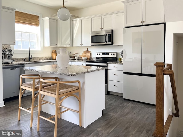 kitchen featuring dark wood-style flooring, a center island, a sink, white cabinets, and stainless steel appliances