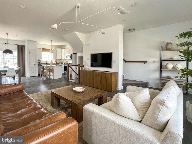 living room featuring stairs, baseboards, and dark wood-type flooring