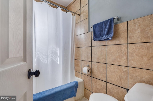 full bath with shower / bath combo with shower curtain, toilet, and tile walls