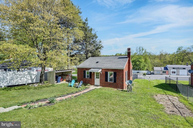 view of front of house featuring brick siding, a chimney, fence, and a front yard