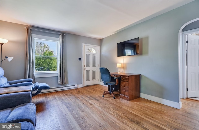 office area with arched walkways, baseboards, baseboard heating, and wood finished floors