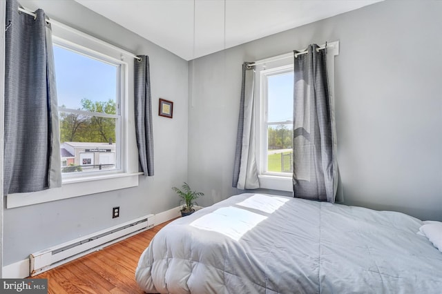 bedroom with baseboards, wood finished floors, and baseboard heating