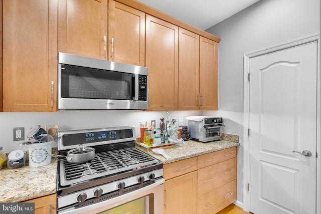 20920 Houseman Ter, Ashburn, VA 20148 - kitchen featuring appliances with stainless steel finishes, a toaster, light stone countertops, and light brown cabinetry