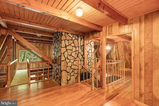interior space featuring wood walls, wood finished floors, wooden ceiling, and beamed ceiling