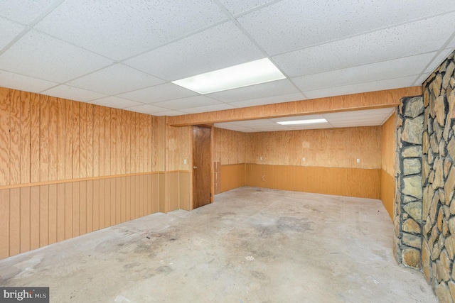 finished below grade area with a paneled ceiling and wooden walls