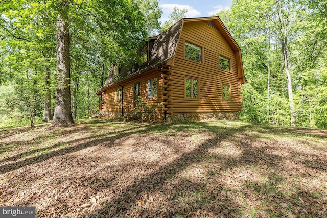 view of side of property with log siding and a gambrel roof