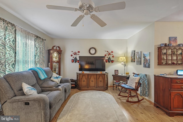 living area with baseboards, ceiling fan, and light wood-style flooring
