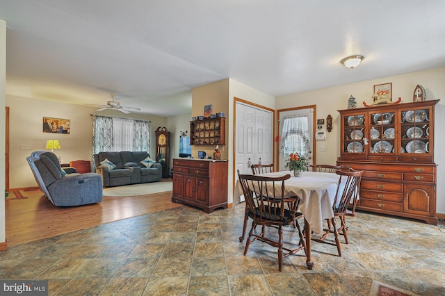 dining area with stone tile floors, a ceiling fan, and baseboards