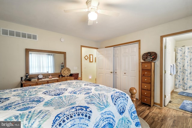 bedroom featuring ceiling fan, visible vents, wood finished floors, a closet, and ensuite bathroom