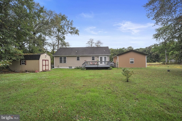 rear view of property with an outdoor structure, a lawn, a wooden deck, and a shed