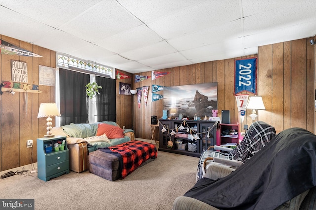 carpeted living area featuring a paneled ceiling and wooden walls