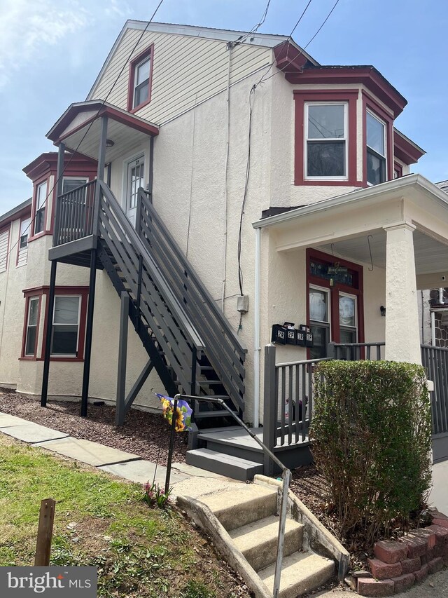 view of front of house with stairs, stucco siding, and a porch