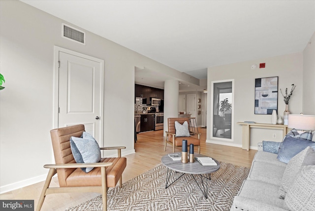 living area featuring baseboards, visible vents, and light wood-style flooring