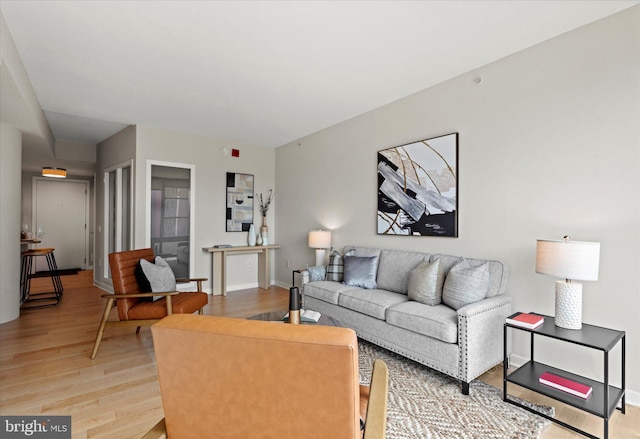 living area featuring baseboards and light wood finished floors