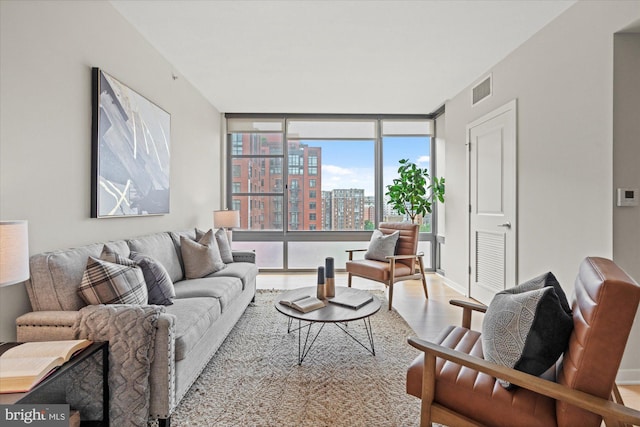 living room with floor to ceiling windows, visible vents, wood finished floors, a view of city, and baseboards