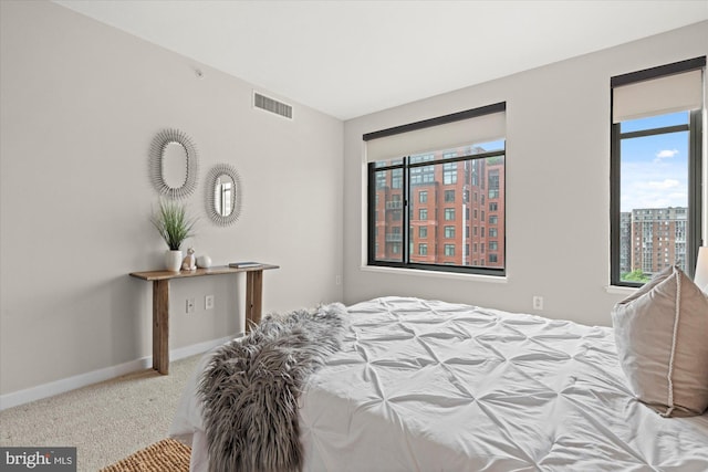 carpeted bedroom featuring baseboards, a city view, and visible vents