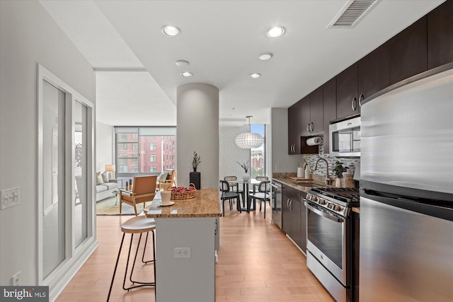 kitchen with appliances with stainless steel finishes, plenty of natural light, a sink, and a kitchen bar