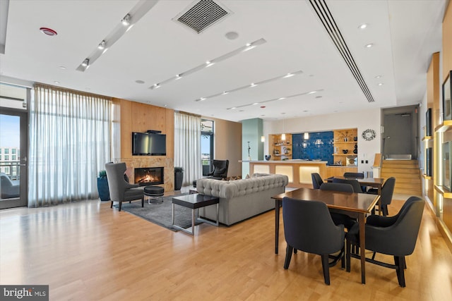 dining area with a fireplace, visible vents, a wall of windows, and light wood-type flooring