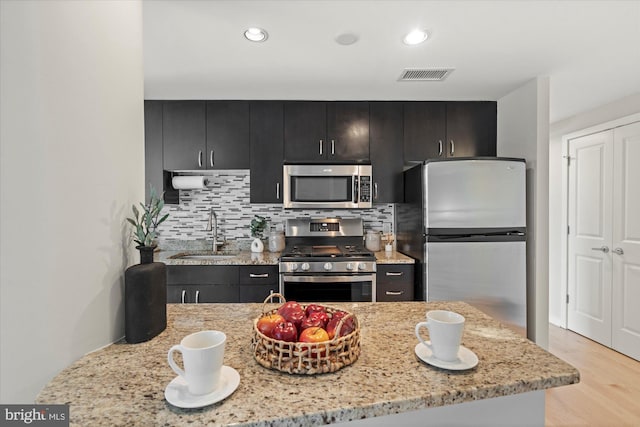 kitchen with dark cabinetry, appliances with stainless steel finishes, a sink, and visible vents