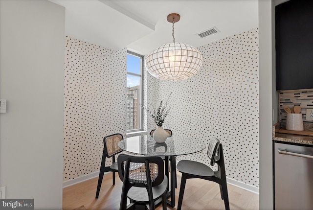dining area with baseboards, visible vents, wood finished floors, and an inviting chandelier