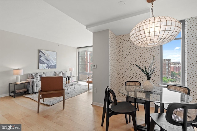 dining room featuring an inviting chandelier, baseboards, plenty of natural light, and light wood-type flooring