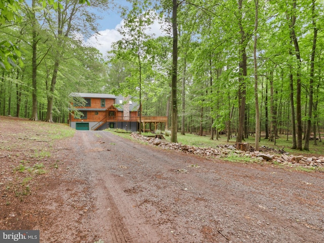 view of road featuring a forest view and dirt driveway